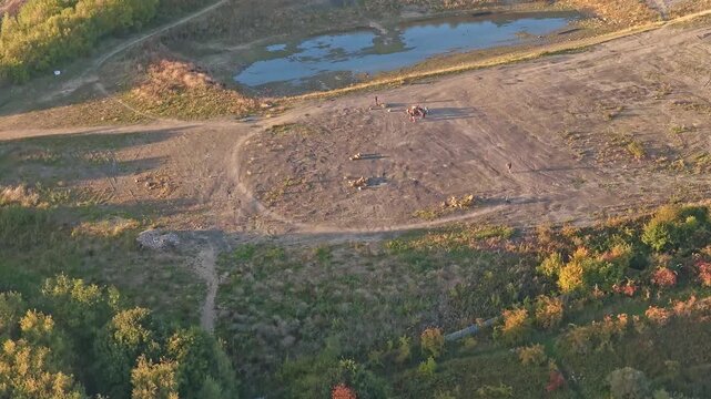 Drone captures the former Sheffield Ski Village, now an open space bordered by autumn forest, dirt paths, and a small pond&mdash;where people gather amid the ruins of a once-thriving sports complex