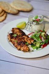Turkish kebab served on a plate with warm pita bread, accompanied by fresh vegetables and traditional sauces. A delicious and authentic presentation of Middle Eastern cuisine.