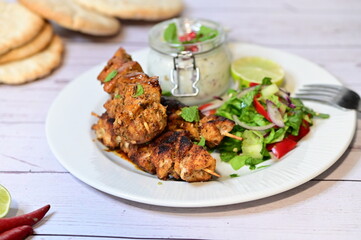 Turkish kebab served on a plate with warm pita bread, accompanied by fresh vegetables and traditional sauces. A delicious and authentic presentation of Middle Eastern cuisine.