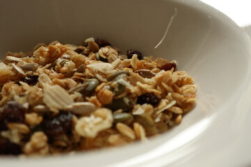 Granola mix filling a white bowl, showing healthy breakfast food ingredients. Cotswolds countryside, England
