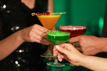 Friends clinking glasses with cocktails in bar, closeup