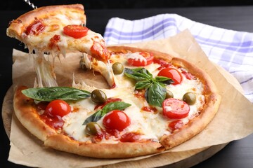 Taking piece of delicious pizza with cheese, tomatoes and olives at grey table, closeup