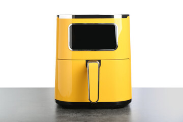 Modern yellow air fryer on grey table against white background