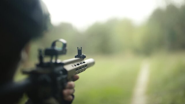 Camouflaged army soldier with AR15 carbine with a collimator on a mission. Close-up. 