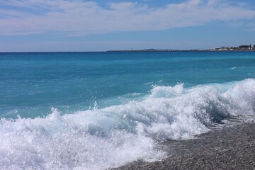 Beautiful view of wavy sea, city and pebbles on beach