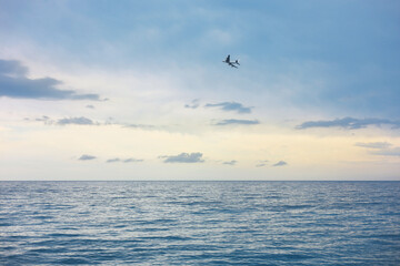 Airplane flying above sea in beautiful blue sky, low angle view