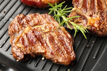Grilled beef steaks, rosemary and peppercorns on black pan, above view
