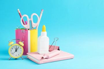 Glue and other stationery on light blue background. Space for text