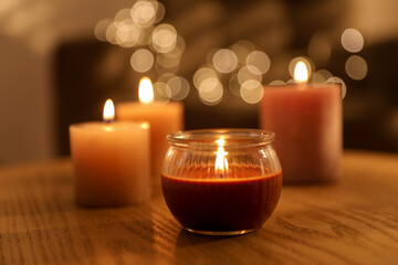 Burning candles on wooden table against blurred lights, closeup