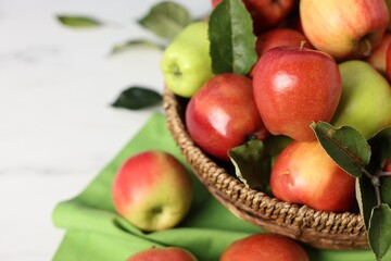 Fresh ripe apples in basket on white table, closeup. Space for text