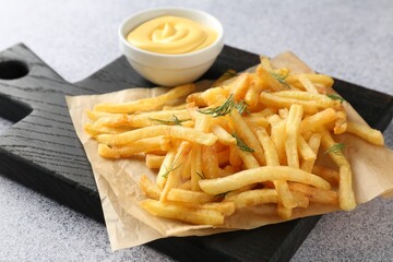 Tasty french fries with sauce on light grey table, closeup