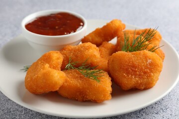 Tasty chicken nuggets with sauce on light grey table, closeup