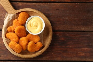 Tasty chicken nuggets with sauce on wooden table, top view. Space for text