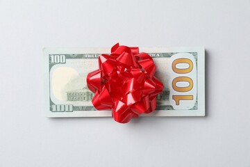 Dollar banknotes with bow on light grey background, top view