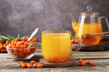 Sea buckthorn tea and fresh berries on wooden table