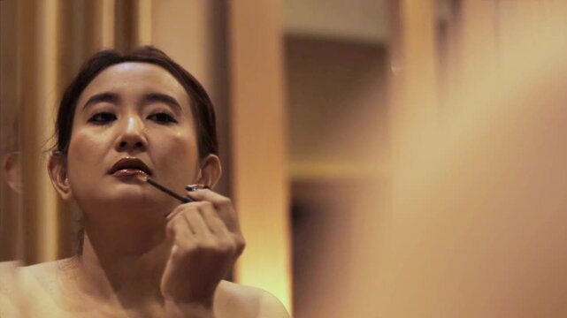 Aesthetic makeup application tutorial by an Asian model in elegant ambiance, demonstrating precise lip gloss