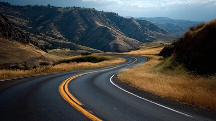 Curving road through rolling hills under a cloudy sky near sunset