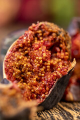 moldy whole and spoiled figs with red flesh and seeds on a table, moldy spoiled figs with lots of grains and red spoiled flesh on a wooden table