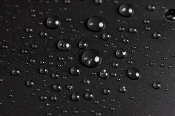 a plastic surface covered with water droplets, details of the wet part of an object made of black plastic