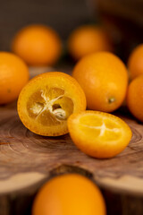 kumquat cut into halves on a wooden table, sliced orange kumquat fruits lie on the table during cooking