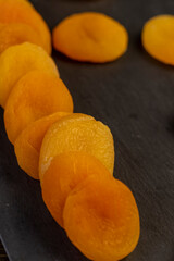 dried ripe orange apricot fruits on a black slate board, dried seedless pure dried apricots for long-term storage and used as a sweet or for making compotes