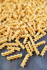 Heap of Uncooked Whole Wheat Fusilli Pasta Scattered on Back Wooden Background