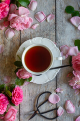 A cup of aromatic tea, a book and a rose on the table.