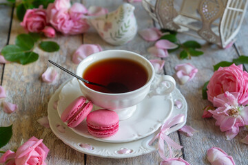 A cup of aromatic tea, a book and a rose on the table.