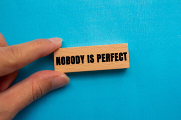 Nobody is Perfect message written on wooden block on blue background. Conceptual Nobody is Perfect...