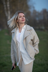 Young woman with short hair wearing oversized white shirt and denim jeans, joyfully dancing against a dark background, expressing happiness and freedom in motion