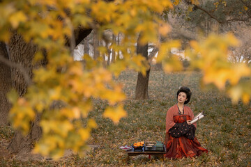 Woman in traditional dress surrounded by autumn foliage, enjoying a peaceful moment in nature.