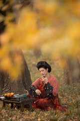 Woman in traditional attire enjoying tea in a serene outdoor setting.