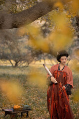Charming woman in a traditional hanfu dress standing in a serene outdoor setting during autumn.