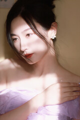 Elegant woman in lavender dress with soft lighting and serene expression.