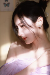 Elegant woman in a soft purple outfit with light ambiance and natural shadows.