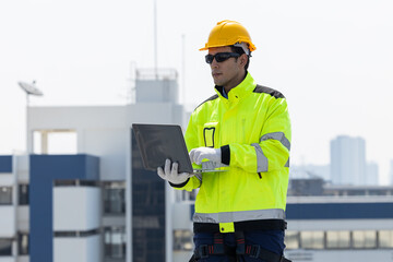 Engineer inspecting solar panels using laptop on rooftop