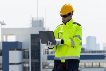 Engineer inspecting solar panels using laptop on rooftop