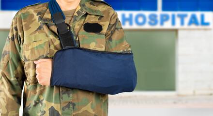 Fototapeta premium Close up of unrecognizable military wearing arm sling with hospital background