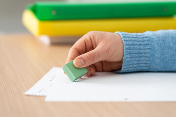Woman hand using rubber erasing pencil drawing on a desk at office