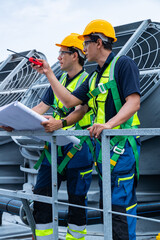 Engineers reviewing blueprints on rooftop HVAC site