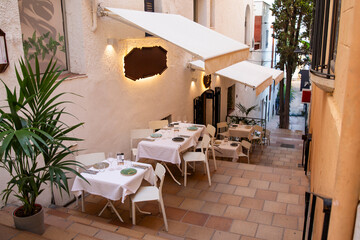 A cozy Mediterranean outdoor restaurant with white tables on the stairs