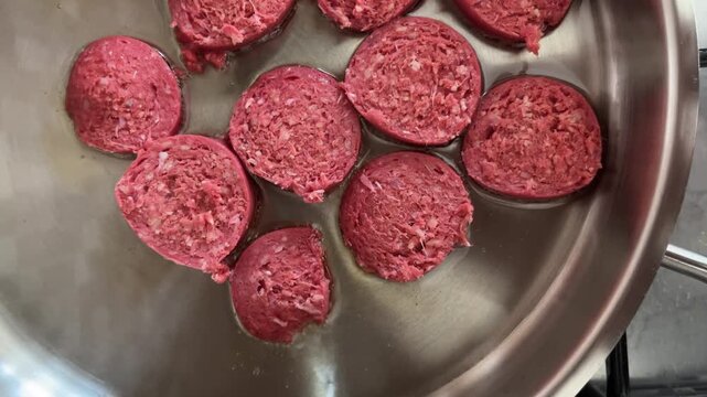Raw slices of Turkish sucuk sausage cooking in sunflower oil pan