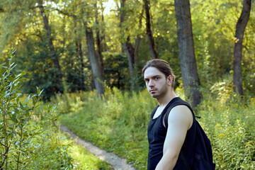 a man walks in the woods with a backpack. Looking into the camera