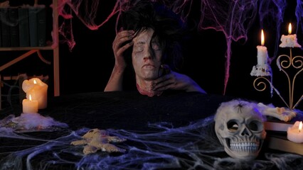Scary zombie hands hold a severed dead head