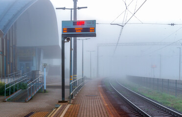 Rail train station in heavy fog in summer morning 