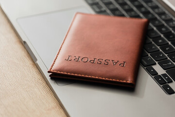 Close-up of a brown leather passport cover placed on a laptop keyboard