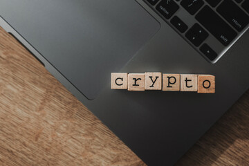 Wooden blocks forming the word “crypto” on a laptop keyboard, representing cryptocurrency, blockchain, digital assets, fintech innovation, and online financial transactions