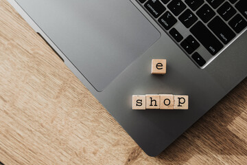 Wooden blocks spelling e shop on laptop, concept of online store and modern e-commerce platform