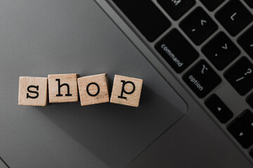 Wooden blocks spelling SHOP on laptop, concept of online retail, digital commerce, and modern shopping platform