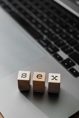 Wooden blocks spelling the word SEX on a laptop keyboard, representing online discussions about gender and sexualit